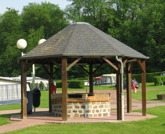 an octagonal wood and slate shelter with brick built barbeques underneath